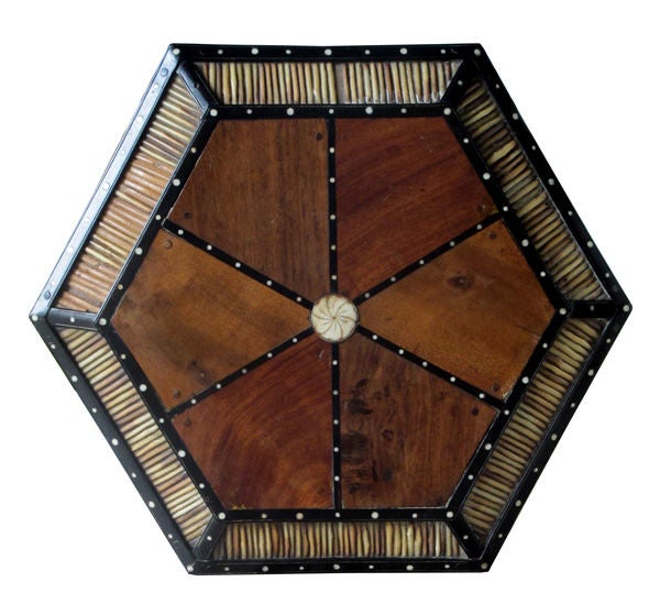 A rare Anglo-Ceylonese ebony and porcupine quill hexagonal table with bone inlay; the hexagonal top of exotic woods with canted quill border; raised on upright rectangular supports joined by a lower conforming shelf; raised on 3 downturned supports