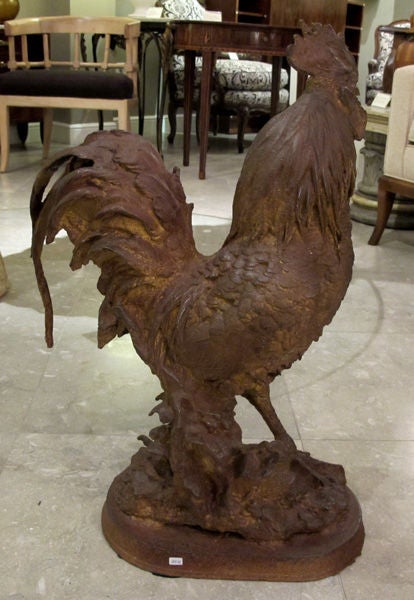 A well-delineated French cast iron rooster; the proudly prancing rooster with cocked head and dramatic comb and waddle above a well-plumed body with exuberant tail feathers; standing on an oval landscaped plinth.