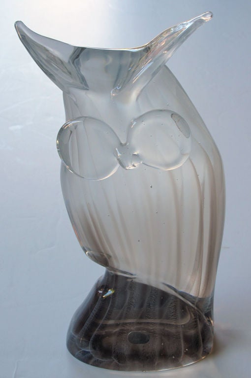 A charming American hand-blown 1960's glass great horned owl; acid etched signature and paper label 'ACC, American Cut Crystal'; the stylized perched owl with horned feathers above large eyes; all in a clear glass with streaks of grey and black