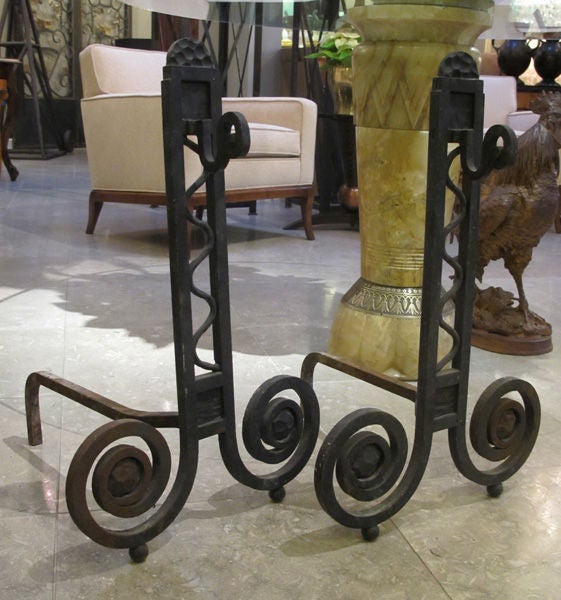 A dramatic and large-scaled pair of French art deco hand-wrought iron andirons; each of open rectilinear form with inset scrollwork detailing above overscaled scrolled feet