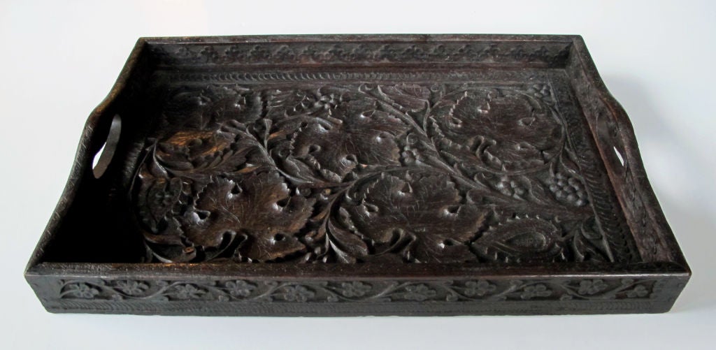 A well-carved German Black Forest rectangular wooden tray; the rectangular tray of lively carved grape vines with robust leaves within an imbricated border; surrounded by a raised gallery with open handles adorned with a carved meandering floral