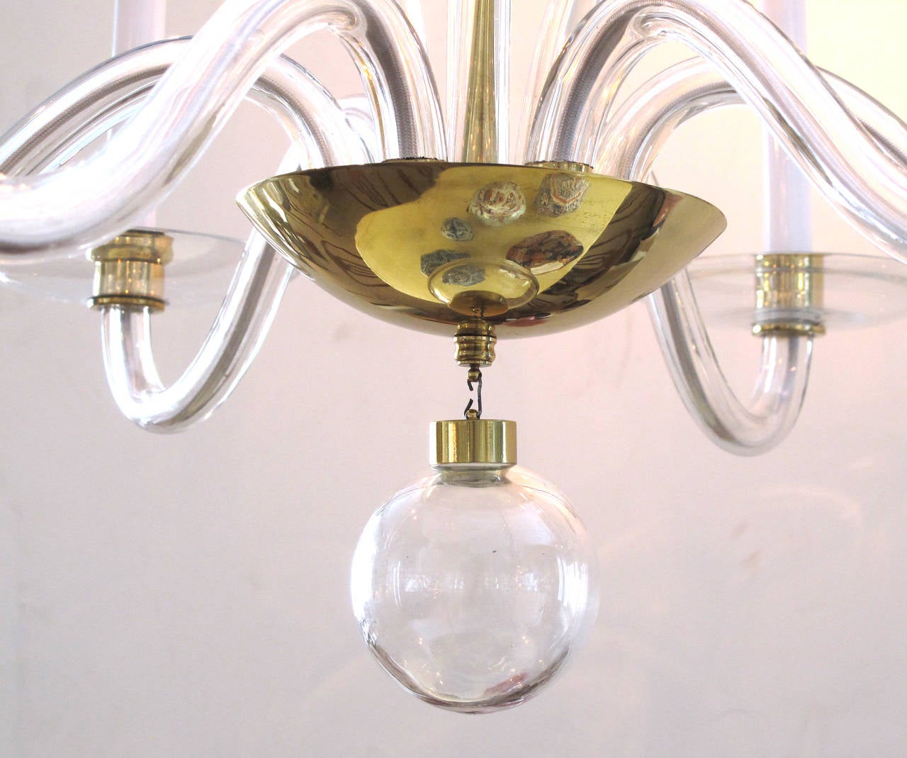 A stylish Murano 1960s clear glass and brass six-light chandelier; the brass bowl emanating upwardly scrolling glass tendrils surrounded by six scrolled arms over a glass spheroid pendant.