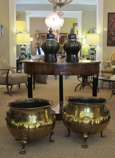 An exceptional and large-scaled pair of English hand-hammered brass lobed jardinieres with lion ring handles; each of grand scale with everted lip above a bulbous lobed body adorned with robust lion ring handles; raised on three curvaceous paw