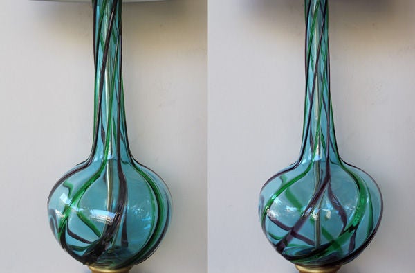 A stunning and large-scaled pair of Italian 1960's gray-blue bottle-form art glass lamps with green and aubergine swirls; each tall lamp with long neck above a bulbous body all of clear gray-blue glass with raised green and aubergine swirls; raised