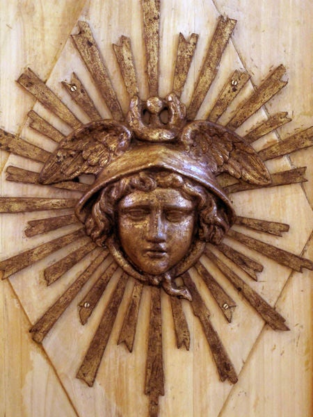 A unique pair of French Louis XVI gilt-metal medallions depicting Mercury now mounted on pine panels; each mounted with a gilt-metal mask of Mercury wearing a winged cap surrounded by radiating spokes; mounted on antique pine panels