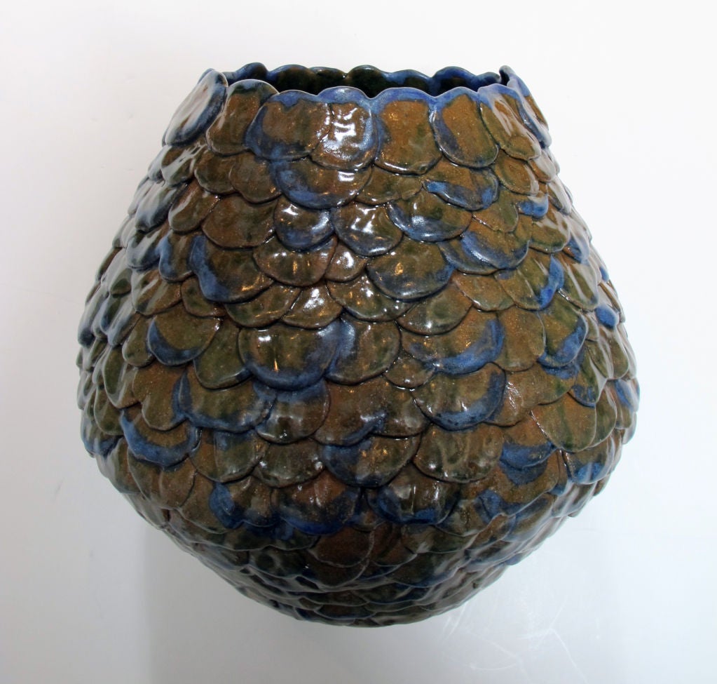 A robust American 1960's art pottery ovoid-shaped pinecone pot; the scalloped opening over an ovoid body with an imbricated surface in modulated green and brown glaze with blue highlights