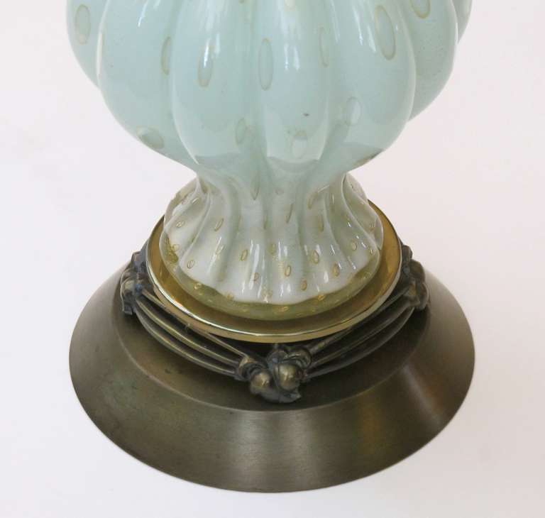 A subtle pair of Murano mid-century ribbed aqua glass lamps with gold inclusions and controlled bubbles; with flaring neck above a portly body over a splayed foot; resting on a brass base