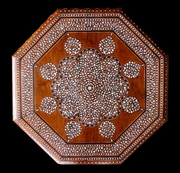 A richly-decorated Anglo-Indian octagonal bone and ebony inlaid traveling table; the attached octagonal top centering a stylized medallion within a border of meandering foliate vines; raised on a conforming base with arabesque openings