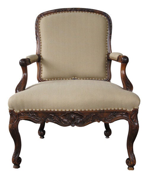 Ein geschwungener offener Sessel aus geschnitztem Nussbaumholz im dänischen Rokoko-Stil; die gerahmte, kartuschenförmige Rückenlehne befindet sich über einem Serpentinen-Sitz, der von verschnörkelten, gepolsterten Armlehnen flankiert wird; die