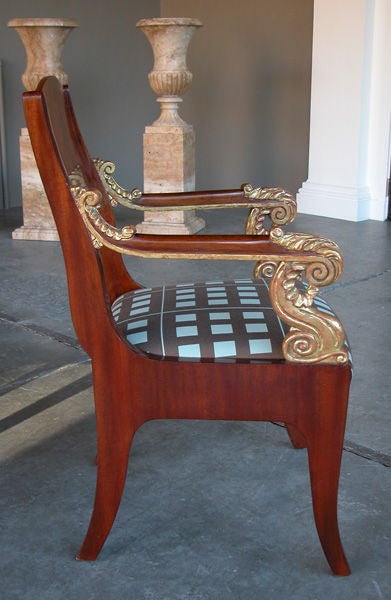 A handsome and regal pair of Russian second empire mahogany and parcel-gilt armchairs; each with flame mahogany back splat flanked by gently sloping arms with lively scrolled terminals all above splayed legs