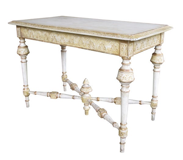 A Danish neoclassical style ivory painted rectangular console/center table with ochre and gilt highlights; the rectangular top with canted intricately carved border and apron finished on all sides; raised on tapering supports with bulbous collars