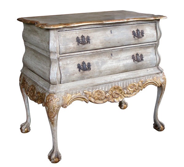 A shapely Dutch rococo style grey-painted and parcel-gilt bombe form 2-drawer chest; the shaped top above a bombe form body fitted with 2 drawers above a well-carved apron with foliate and rocaille decoration all raised on graceful cabriole supports