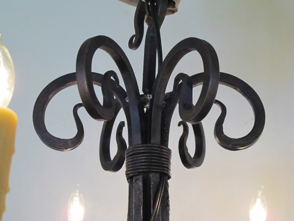 A gracefully shaped French hand-wrought iron 6-light chandelier; the 6-light chandelier composed of dramatic iron scrollwork supporting shallow bobeches