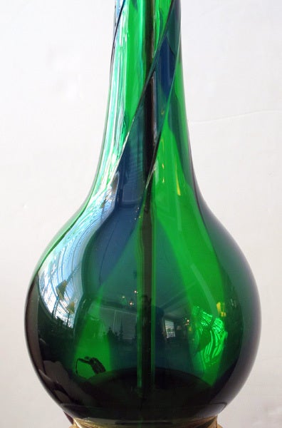 A sleek and stylish pair of Murano mid-century emerald green and cobalt blue swirl bottle-form lamps; each with long slender neck above a bulbous body all in a rich green and blue swirl glass; raised on a reticulated gilt metal base