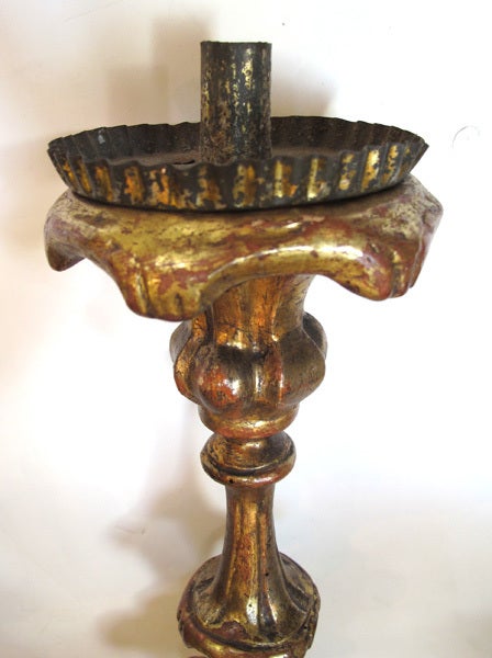 A boldly-scaled Italian baroque carved giltwood candlestick; with tole candlecup above a well-carved graduated support raised on a tripartite base