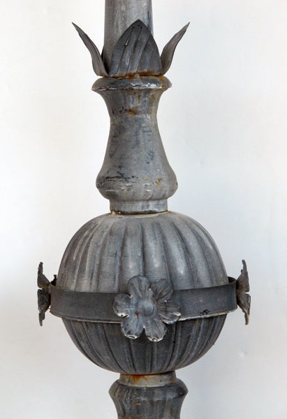 A striking and tall pair of French Napoleon III zinc roof finials; each with slender pointed spire above a fluted spheroid mid-section adorned with flower heads; all raised on a flared base resting on a later ebonized wooden plinth