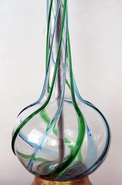 A striking and tall pair of Murano art glass bottle-form blue and green swirl lamps; each with tall neck above a portly body all in a clear glass with raised blue and green swirls; raised on a giltwood base