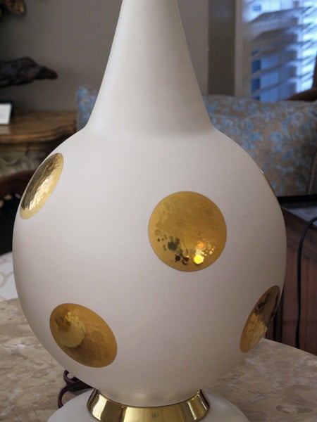 A stylish pair of American mid-century ivory ceramic spheroid lamps adorned with gilt circles; each with long graduated neck above a robust spheroid body with gilt dots resting on a circular splayed base