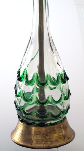 A shimmering pair of Murano 1950's clear bottle form lamps with raised green swirl decoration; each with long neck above a bulbous body adorned with continuous green swirl decoration; raised on splayed giltwood bases