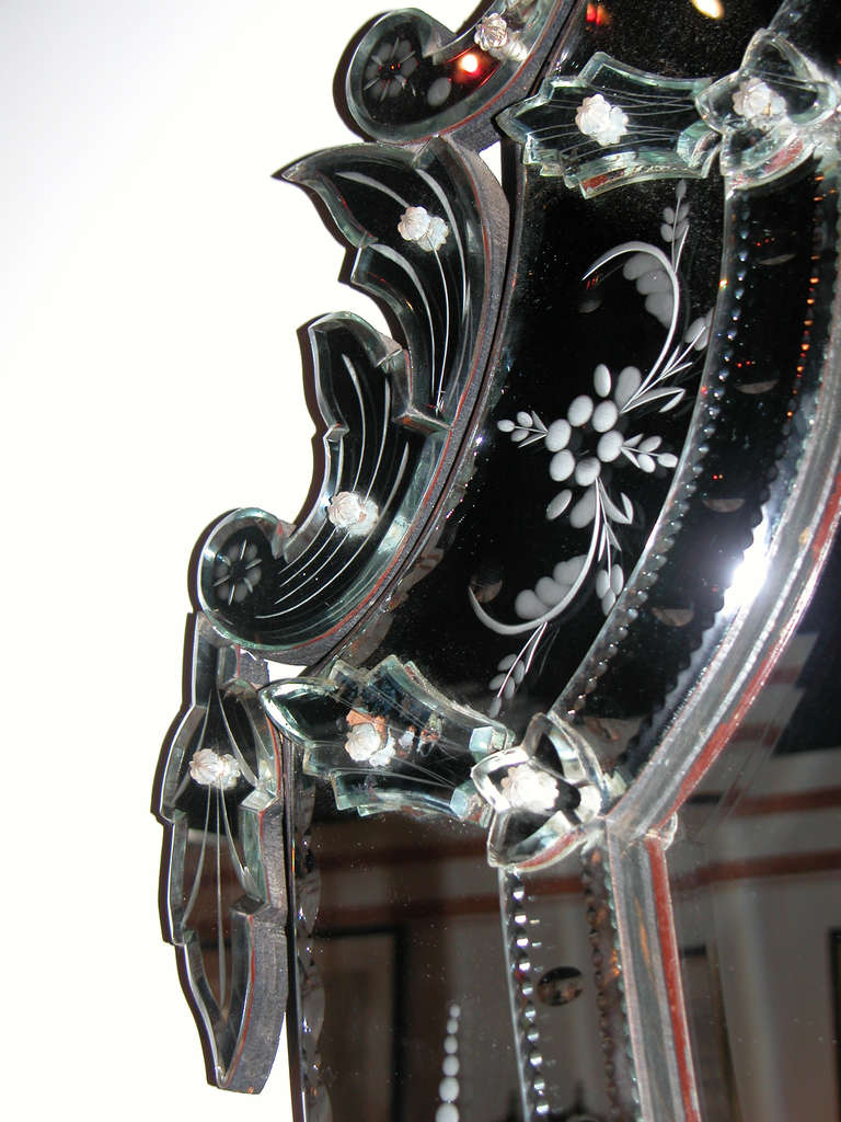 A stunning and large-scaled Venetian neoclassical style shield-form mirror; the beveled shield-form center plate surrounded by an etched mirrored outer border; the whole surmounted by an exuberant crest