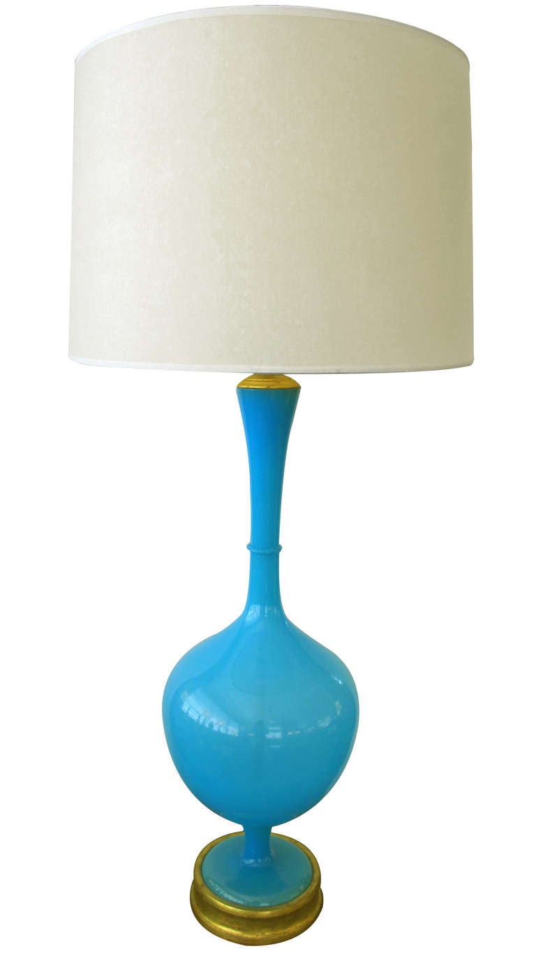 A tall and slender Swedish mid-century vibrant blue art glass bottle-form lamp; for Marbro Co.; the flared neck over a bulbous mid-section raised on a short stem over a circular base; all raised on a circular giltwood plinth