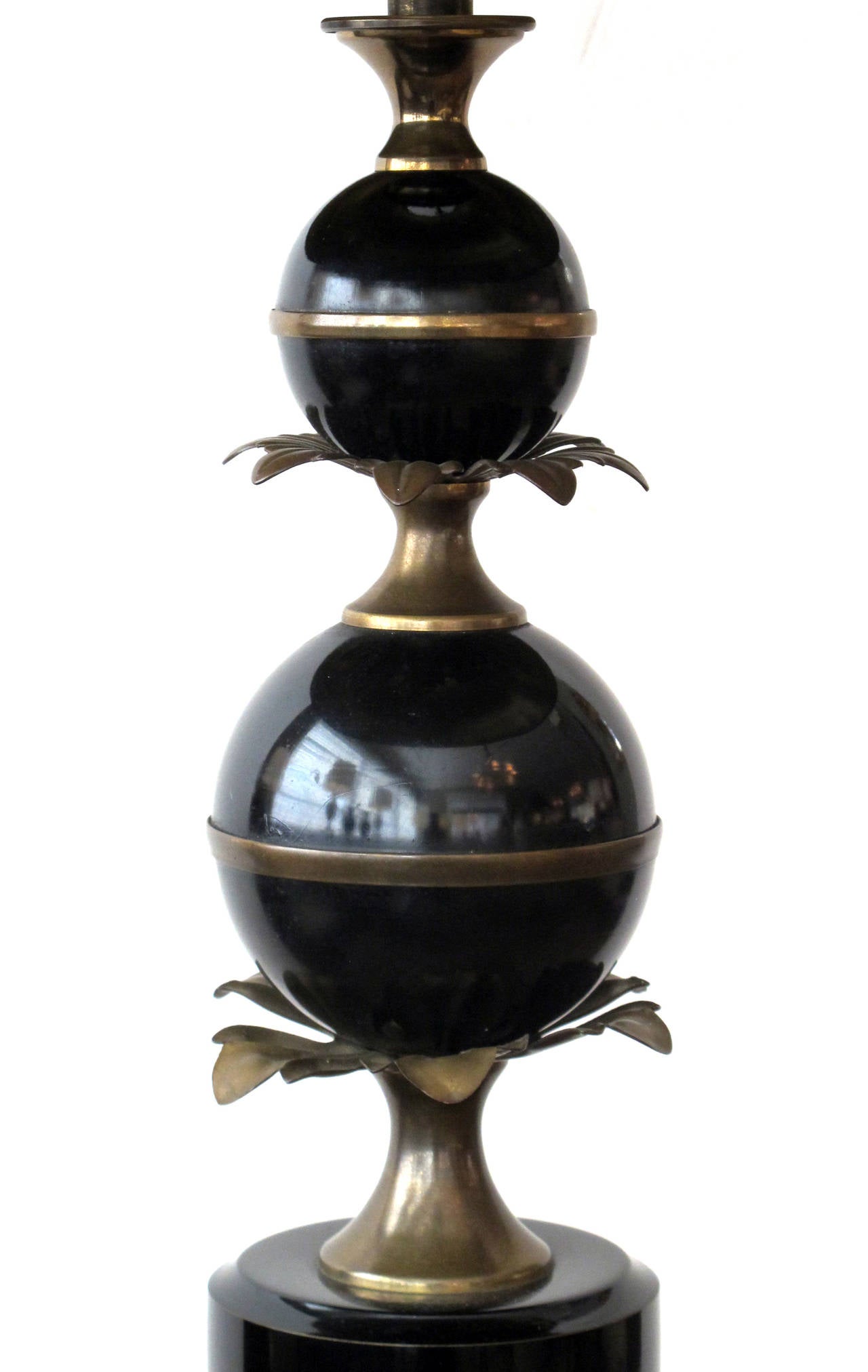 A stylish French 1940s black tole lamp with brass foliate mounts; of graduated spheres over a cylindrical base fitted with flaring foliate mounts