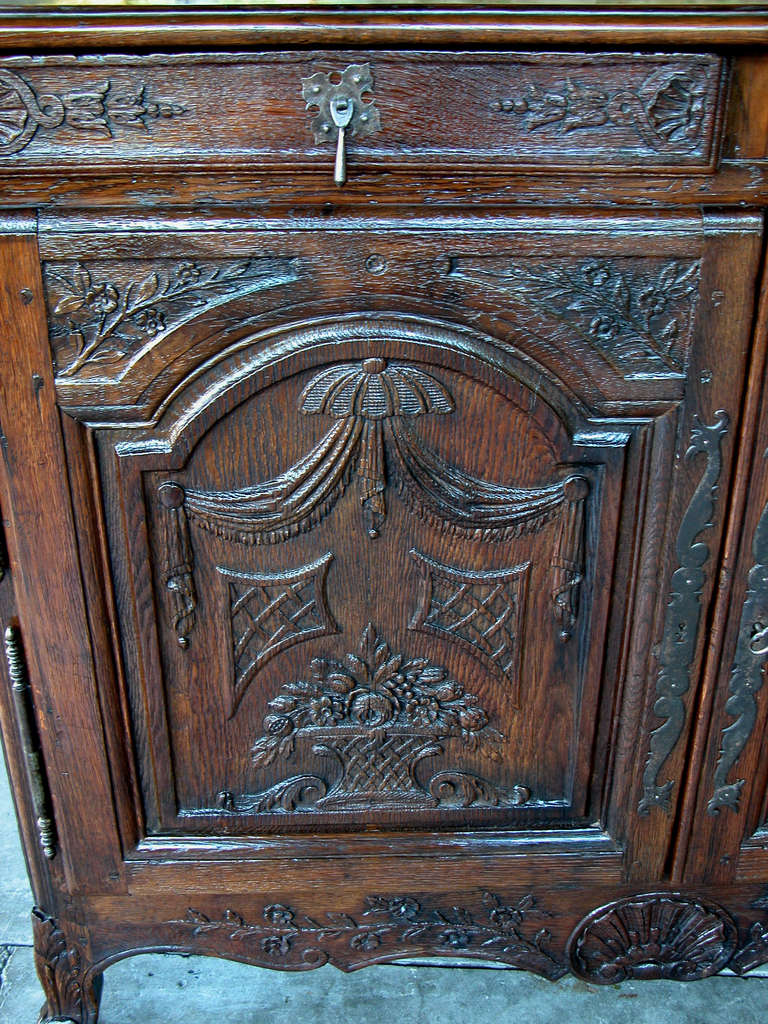 A richly-patinated and well-carved French provincial oak 2-door buffet; the rectangular top with diamond inlay above a conforming body with 2 short frieze drawers above 2 doors carved with draped festoons and floral baskets; the scalloped apron