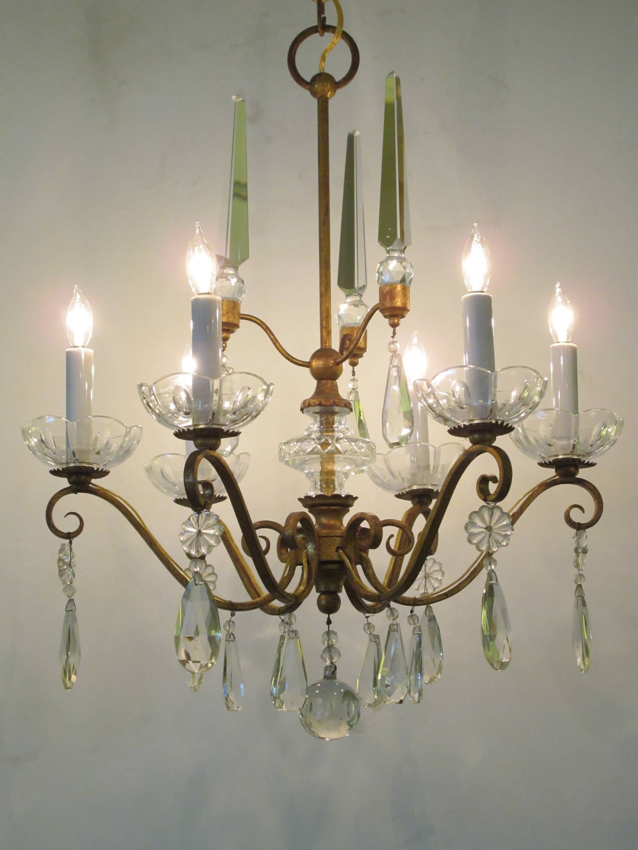 An elegant French 1940s gilt-metal six-light chandelier with crystal pendants; the gilt metal frame emanating six scrolling arms; adorned overall with three crystal obelisks and multiple pendants