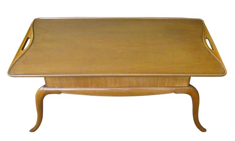 A chic and stylish Italian midcentury pearwood cocktail table with graceful splayed legs; the rectangular top with glass inset flanked by open handles; over a thick apron raised on elegant splayed supports.