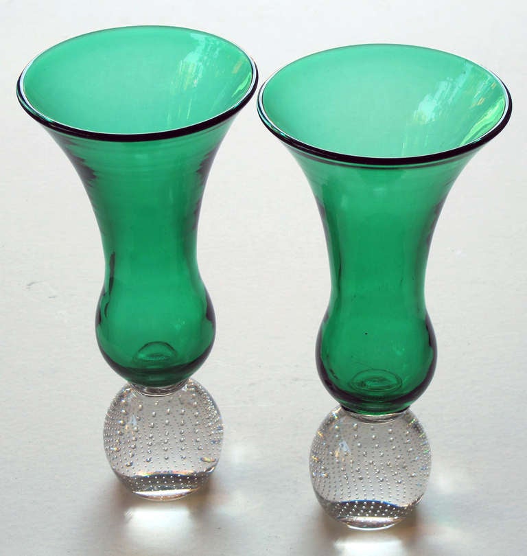 A shapely and good quality pair of American emerald-green trumpet vases by Pairpoint Glassworks; each tall vase with everted mouth above a bulbous body; all-over a spheroid clear glass base with controlled bubbles.