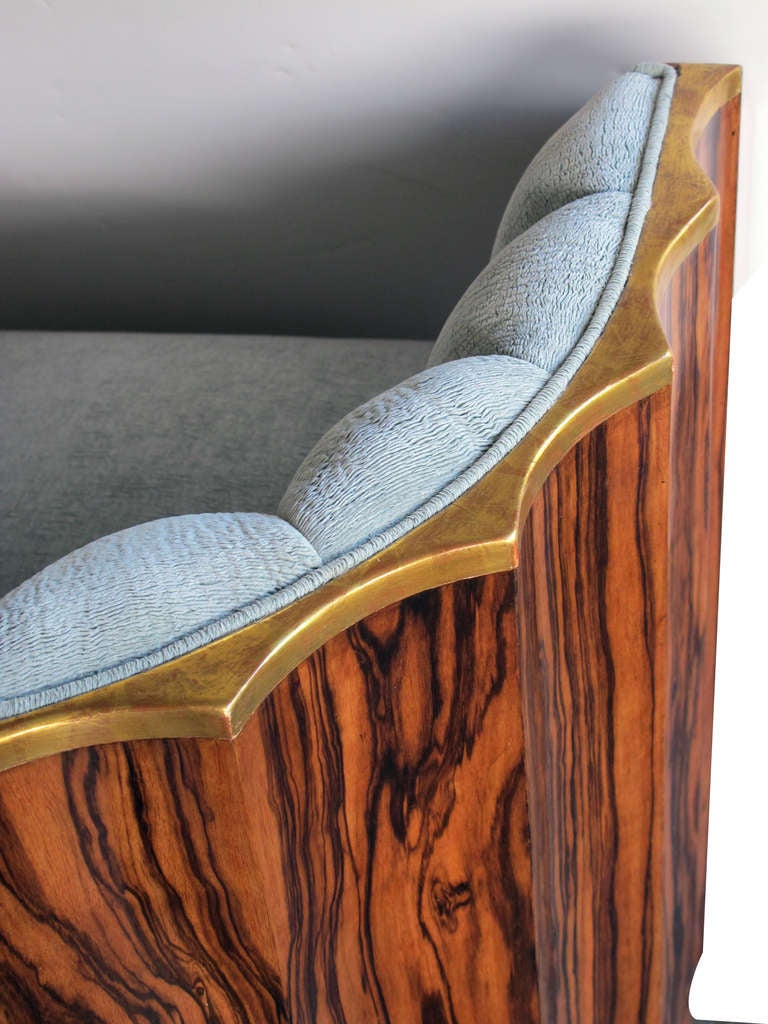 An exceptional and shapely pair of French art deco black walnut club chairs with scalloped backs; each with incurved padded back above a u-shaped seat; with scalloped giltwood crest rail above a conforming and well-figured black-walnut veneered