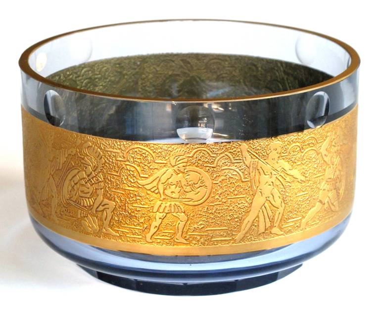 A good quality amethyst art glass circular bowl with gilt-frieze; by Moser Glass Works (with foil label); the dimpled rim above a gilt-frieze of archers and warriors all raised on a faceted foot.