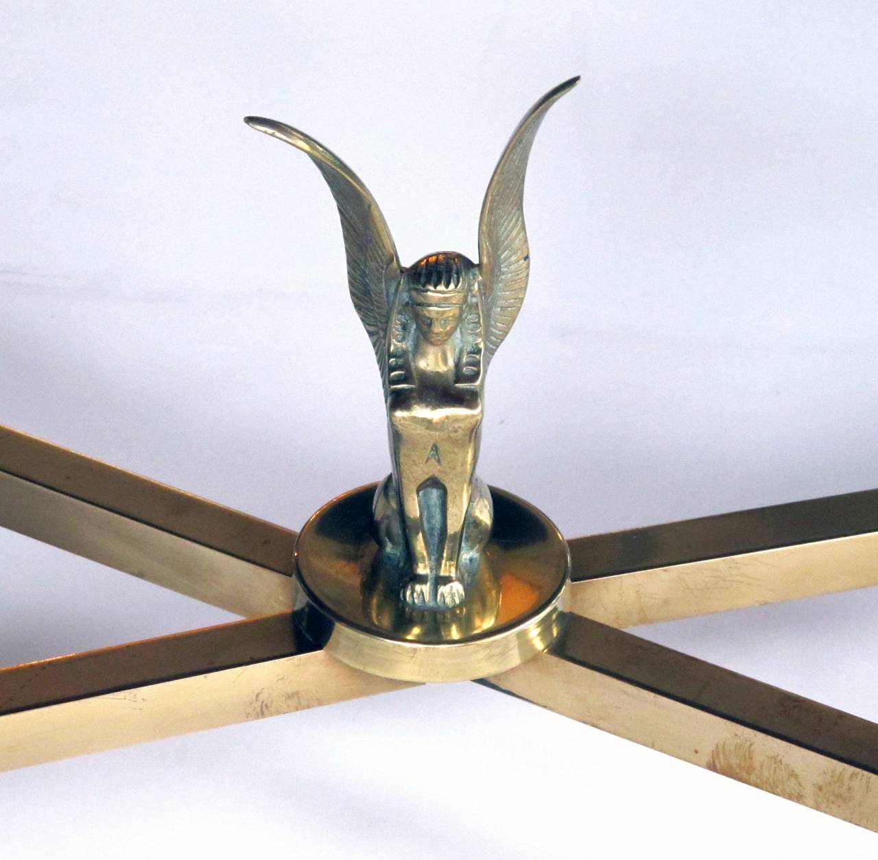 A stylish and good quality French mid-century neoclassical style brass coffee table; the antiqued mirrored inset top raised on 4 tapering fluted square supports all joined by an x-form stretcher centering a winged sphinx