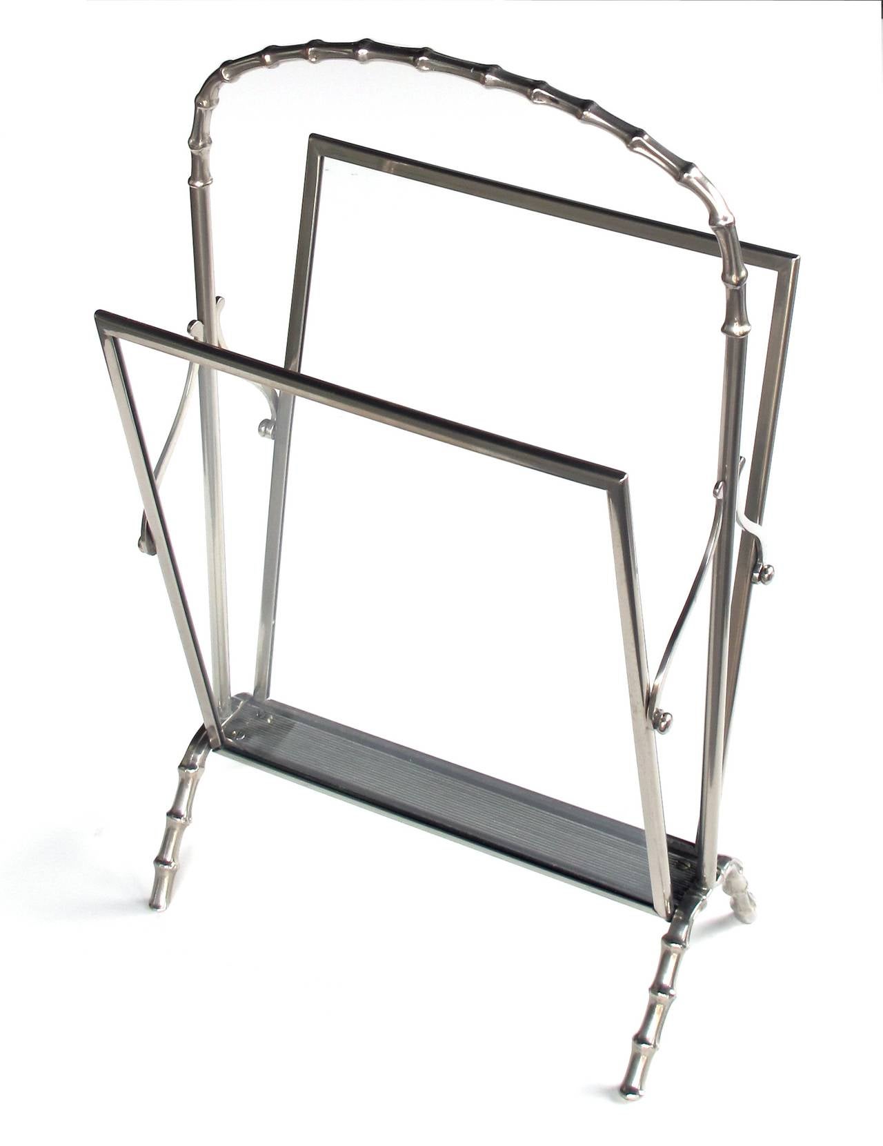 A chic and stylish French Maison Bagues 1940's chrome faux bamboo magazine rack; with arching faux bamboo handle joining a glass framed receptacle over faux bamboo legs
