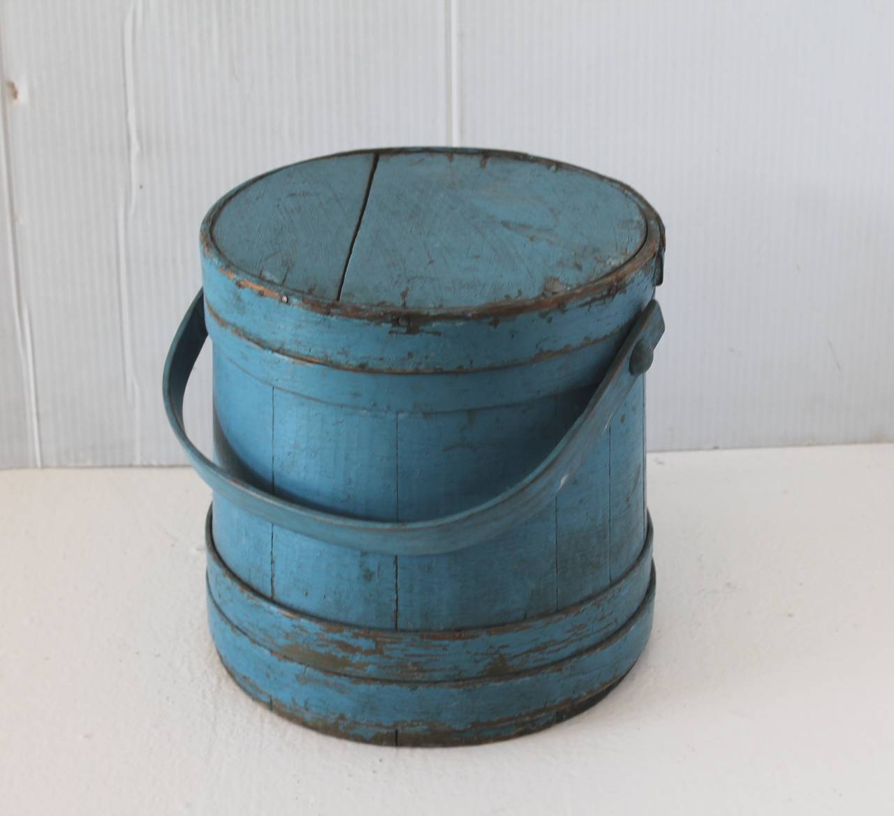 This fantastic and vibrant light blue over green painted firkin was found in Maine. The condition is good with minor wear consistent with age and use. Minor age crack on top lid does not take away from the beauty and condition of the bucket.