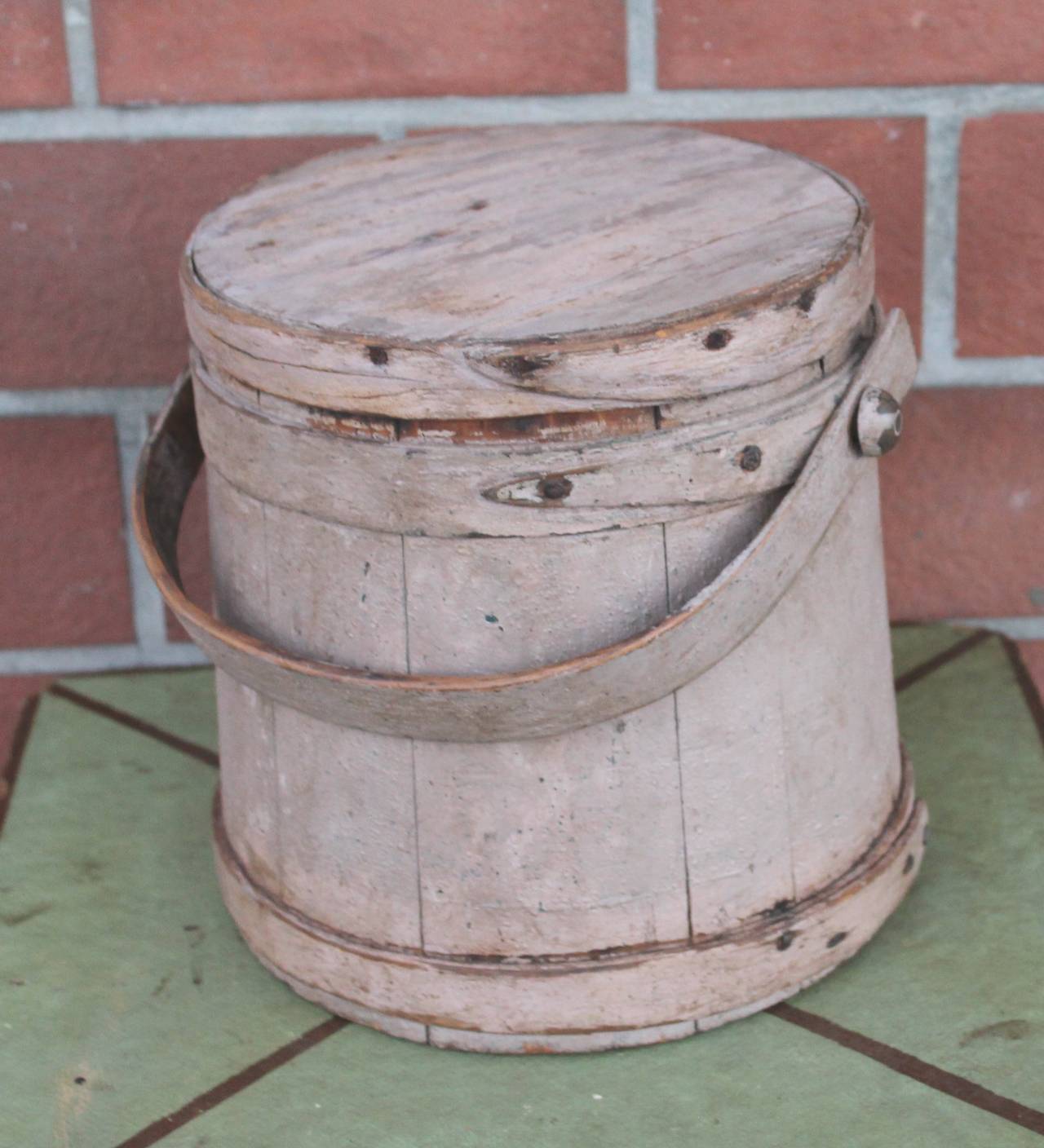 This worn and grungy 19th century painted dusty rose over dark blue painted firkin or handled bucket is in good as found condition. The early hand made rose head nails are all in tact. This bucket has shaker like finger bands. The top is 8 3/4