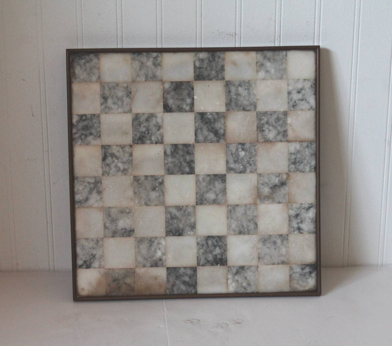 Amazing early 20th century alabaster checker board with a wonderful and original brass picture frame molding. This trim molding has a great aged patina surface. The body of the board has a nature worn hues and a very wonderful old surface. The