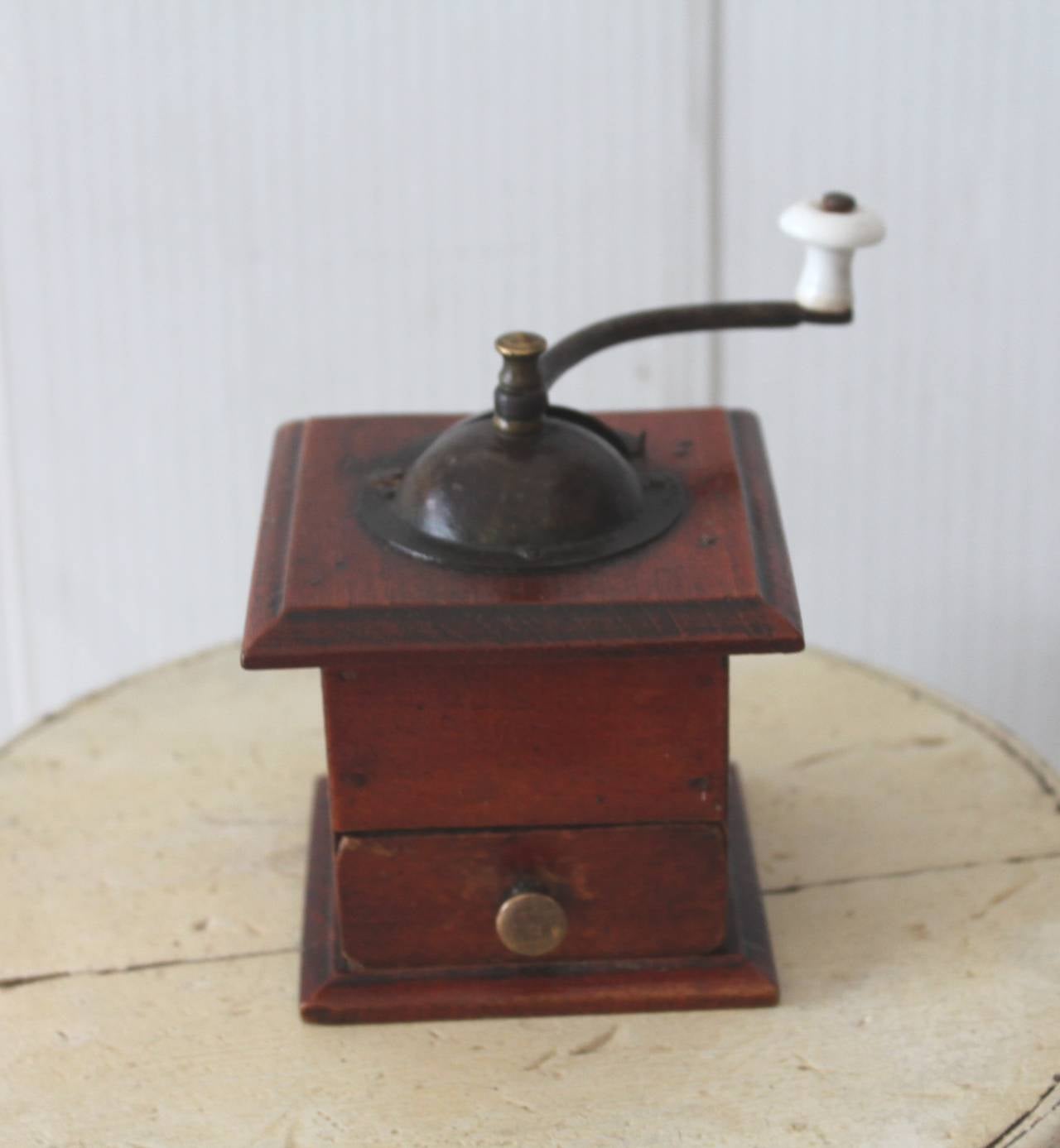 This finely constructed miniature 19th century coffee grinder has all original hardware and early pin nailed construction. The drawer pull is a brass Shaker Style pull with a iron stone knob on grinder handle. Condition is pristine.