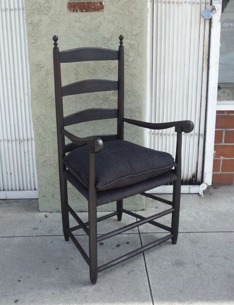 This early NE. ladder back  arm chair retains a early untouched black painted surface . The form is the very best and the black linen seat is newly finished  w/ a down filled custom cushion . This chair is in a very sturdy condition and is most