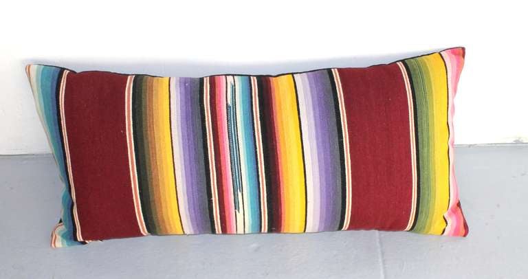 This colorful handwoven Mexican serape is a bolster size great on a bed or sofa. The back is in black cotton linen. The insert is down and feather fill. There are three in stock and sold individually.