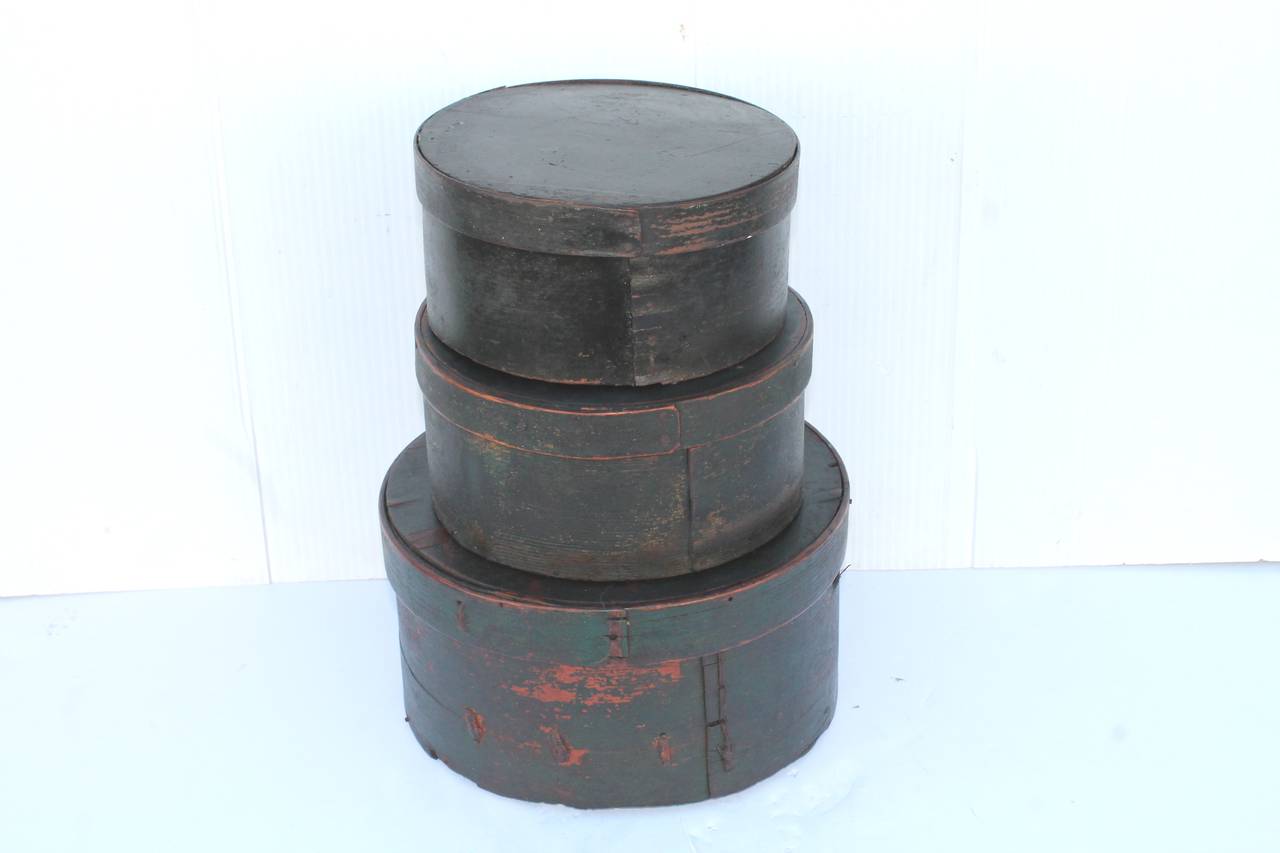 These grungy green 19th century original painted pantry boxes were found in New England and are being sold as a stack. The condition are good and sturdy, however the largest of the stack has minor cracks consistent with age and use. The smallest is