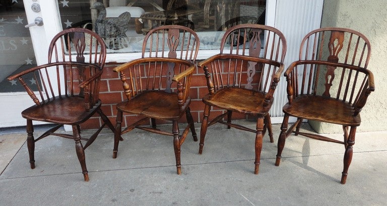 Fantastic surface and old worn patina set of four English Windsor arm chairs.These extended arm chairs are very comfortable and sturdy.The seats are a wonderful saddle seat.All of them have their own wear and personality .Great around a round table 
