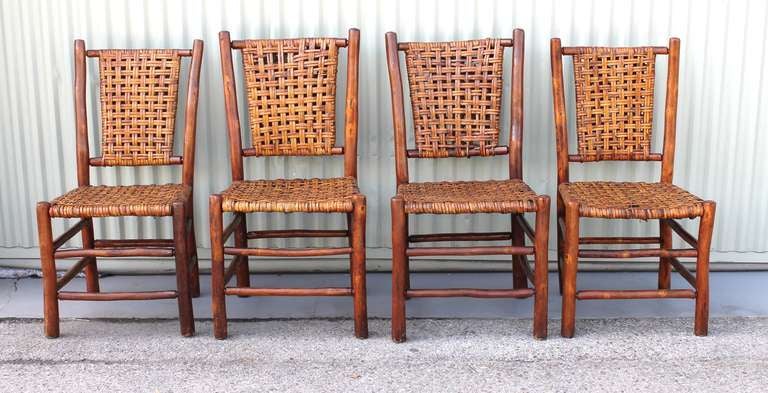 Ce merveilleux ensemble de quatre chaises non signées en Old Hickory provient du célèbre Mission Inn de Riverside:: en Californie.  Les chaises ont conservé non seulement leur surface ancienne d'origine:: mais aussi les sièges et les dossiers