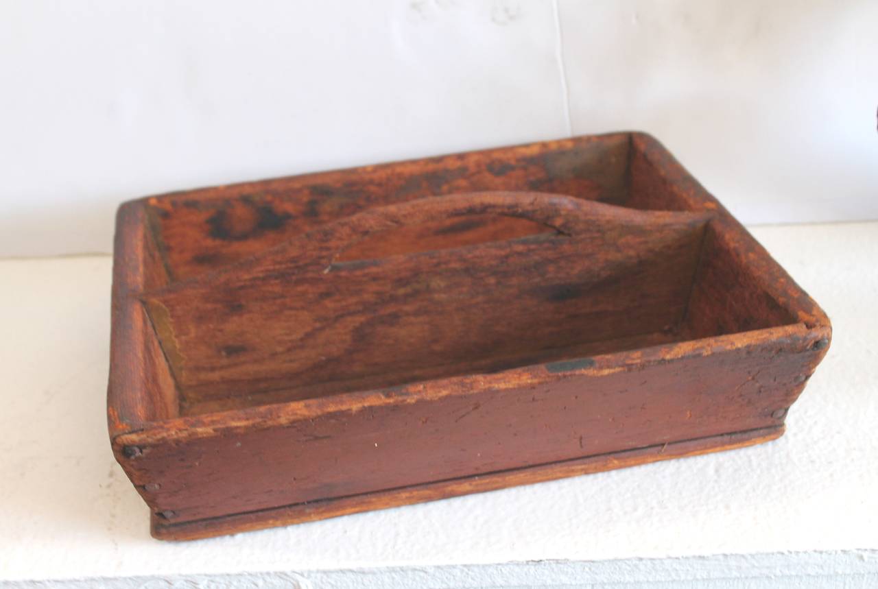 This 19th century original red painted cutlery carrier or box has a nice hand-carved or cut-out handle. It is all handmade and square nail construction. Found in Pennsylvania.