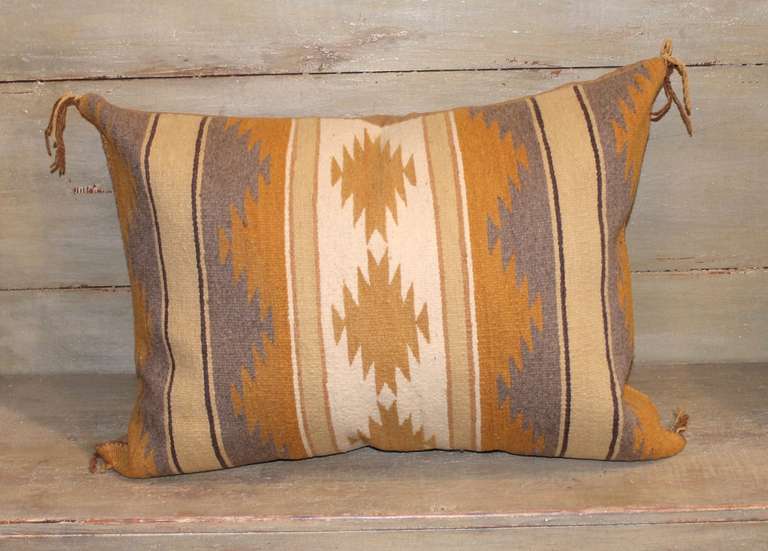 This strong and subtle Chinle Navajo woven pillow shows a classic geometric patterning of alternating sizes of restrained colored stripes utilizing natural greys, tan, gold and taupe as a backdrop to grey and mustard bands of woven squash blossoms. 