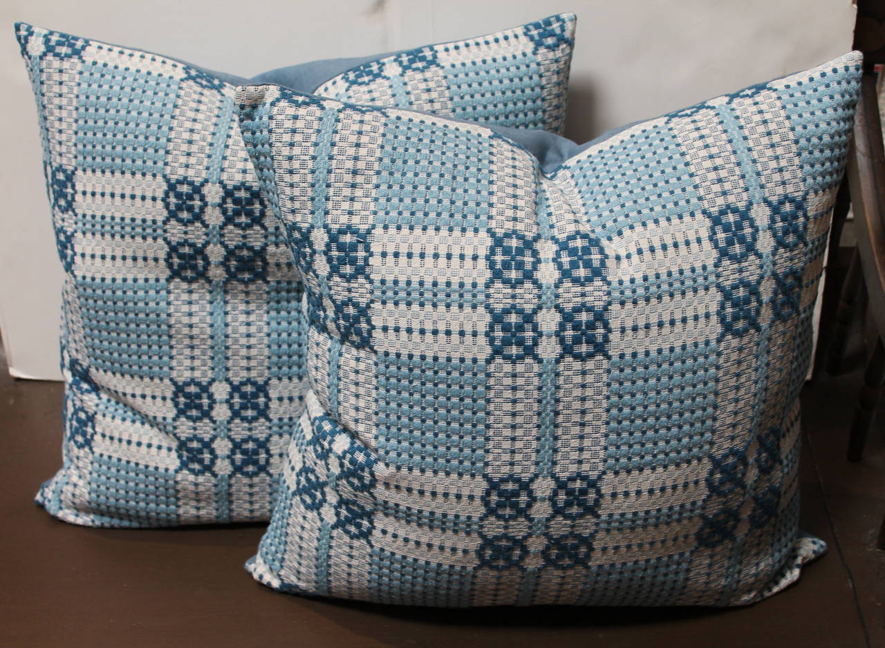 19th century woven jacquard coverlet pillows in light shades of blues. The backing is in a cotton robin egg blue linen. The inserts are down and feather fill. There are three pairs in stock.