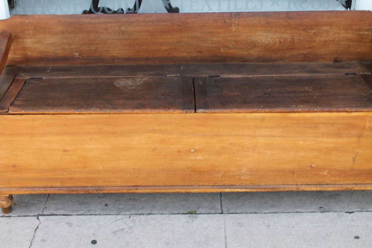 This early boot box or storage box bench was found in a Pennsylvania farmhouse and has a wonderful worn patina. The construction is square nailed and dovetailed case. The turned feet are all original with wonderful cut-out arms for the bench. This