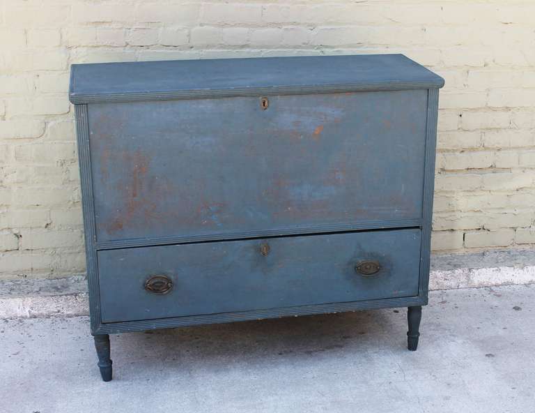 This blue over blue original painted blanket chest over drawer dates to the second quarter of the 1800’s, New England.   With a picture frame molded lift-top, this piece is in structurally excellent condition showing square nail and dovetail