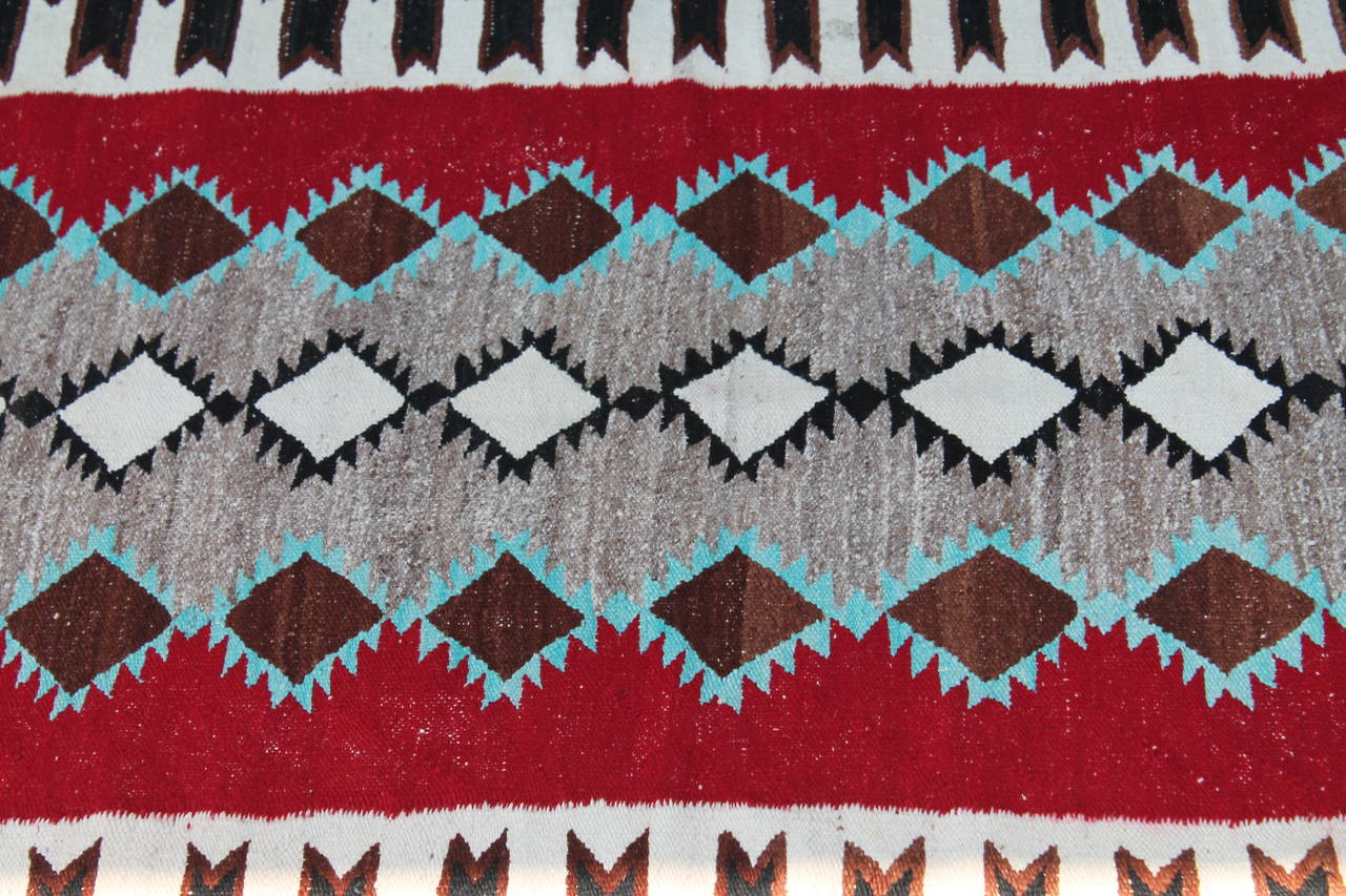 This fine Navajo weaving has miniature flying geese blocks and tail feather borders. The colors are quite unusual and the condition is very good.