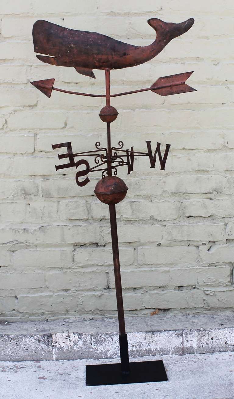 This late 19th century three dimensional original salmon pained sheet iron weather vane is fashioned in the shape of a swimming whale and is a fantastic example of New England folk art.   Set atop a hand forged arrow and decoratively attractive